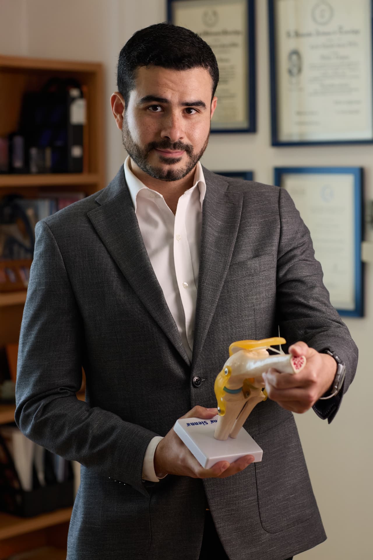 Dr. Rolando Garmendia Pulido con modelo anatómico de rodilla en su consultorio